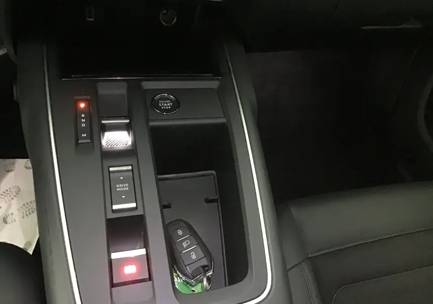 Vue rapprochée de la console centrale noire du Citroën C5 Aircross 2024 avec clé mains libres posée et boutons lumineux.