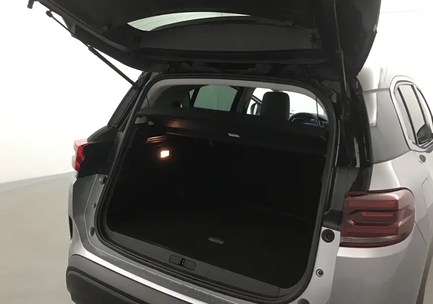 Vue arrière ouverte du Citroën C5 Aircross gris Artense/noir, montrant le coffre spacieux et l'éclairage intérieur allumé.