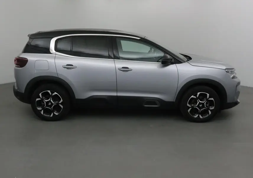 Profil côté droit du Citroën C5 Aircross 2024 gris Artense avec toit noir et jantes spécifiques en alliage.