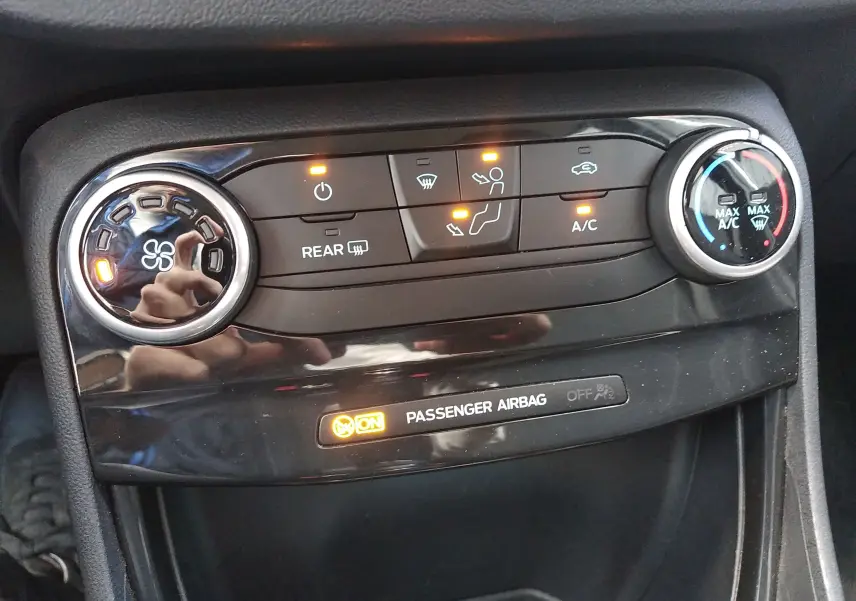Gros plan sur la console de climatisation du Ford Puma blanc 2021 avec commandes et témoin airbag passager allumé.