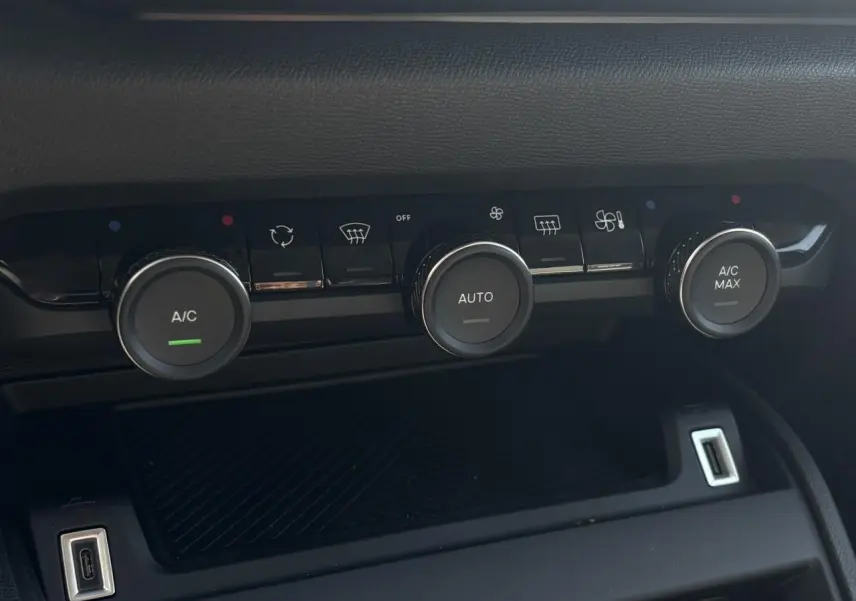 Gros plan sur les commandes de climatisation automatique de la Citroën C4 Hybrid blanche, avec boutons rotatifs et ports USB visibles.