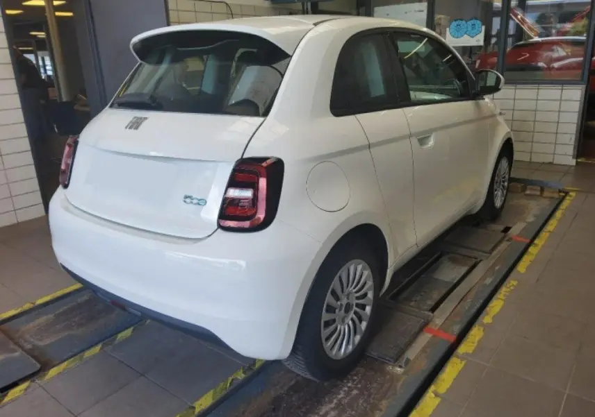 Vue 3/4 arrière droite d'une Fiat 500 électrique blanche 2024, avec feux arrière LED et jantes spécifiques Icone.