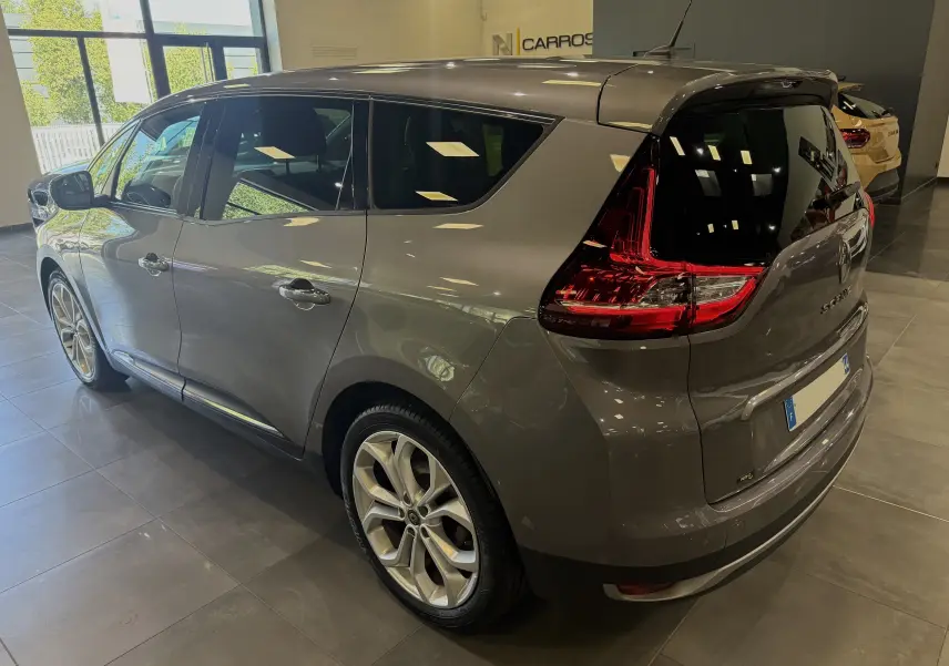 Renault Grand Scenic IV Business gris Cassiopée vu en 3/4 arrière droit dans un showroom lumineux.