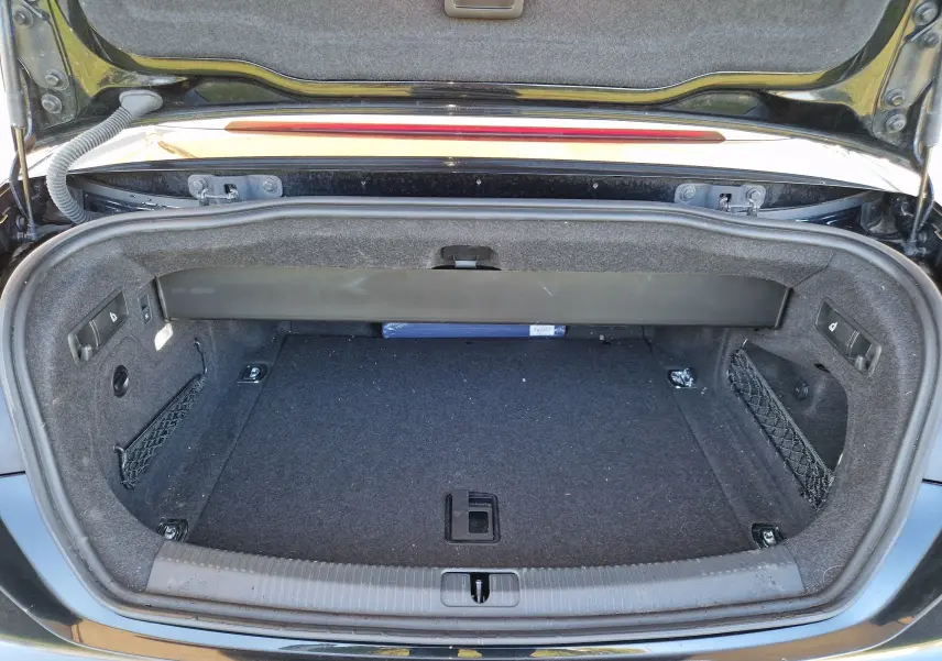 Coffre ouvert vu de face d'une Audi A5 Cabriolet noire de 2017, intérieur du coffre tapissé de moquette grise.
