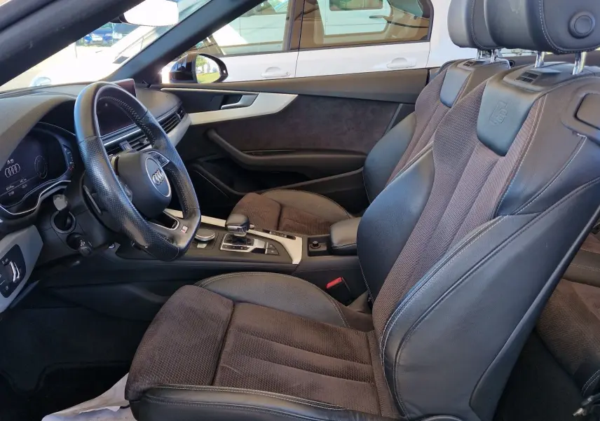 Vue intérieure côté conducteur de l'Audi A5 Cabriolet noire de 2017, mettant en valeur les sièges cuir et alcantara ainsi que le volant multifonction.