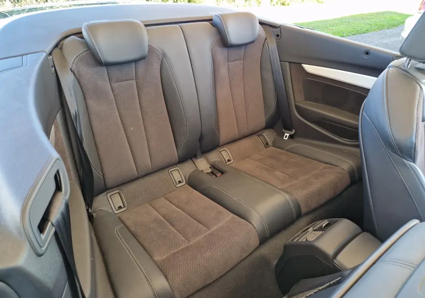 Vue intérieure arrière de l'Audi A5 Cabriolet 2017 noire, montrant les sièges arrière en cuir et tissu marron.