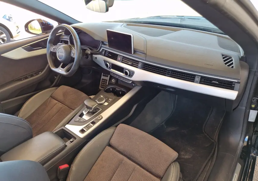 Intérieur de l'Audi A5 Cabriolet 2017 noir, vue côté conducteur, tableau de bord moderne avec écran central et volant cuir.