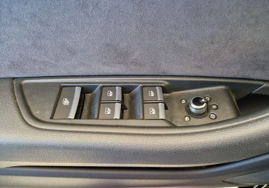 Gros plan sur les commandes de lève-vitres et réglage des rétroviseurs côté conducteur d'une Audi A5 Cabriolet noir 2017.