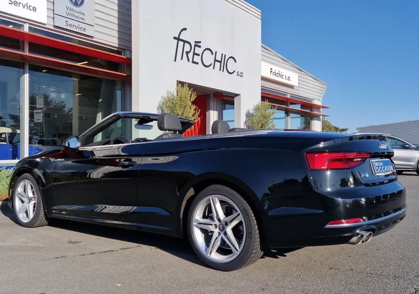 Audi A5 Cabriolet noir vue 3/4 arrière côté droit, capote ouverte, jantes alliage et double sortie d'échappement visibles