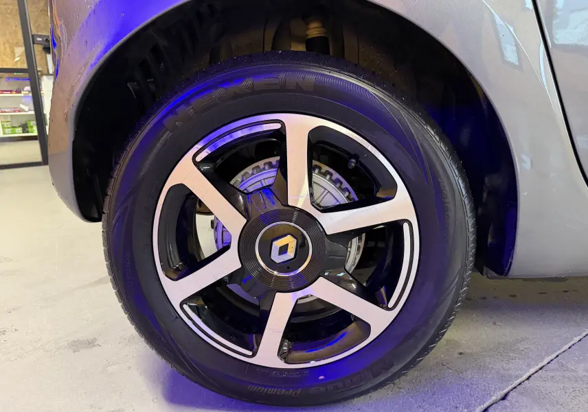 Gros plan sur la roue avant droite grise d'une Renault Twingo III 1.0 TCE 90 Intens avec jante alliage bicolore.