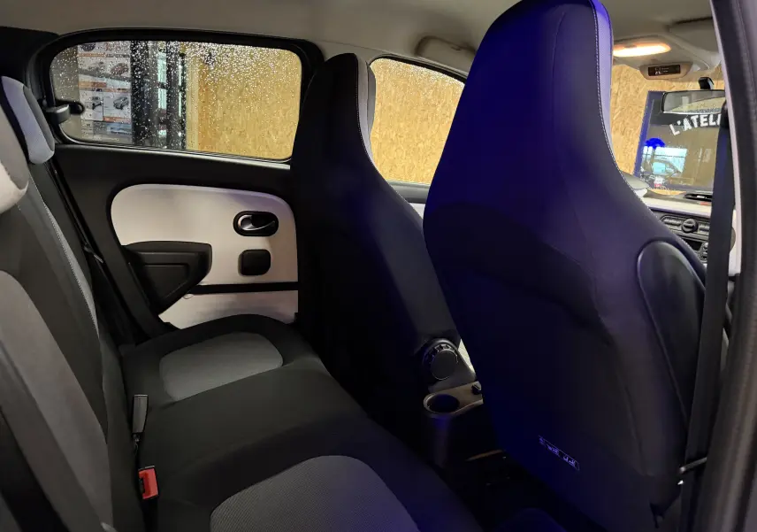 Vue intérieure arrière droite de la Renault Twingo III 2018, sièges tissu noir et gris avec portes bicolores.