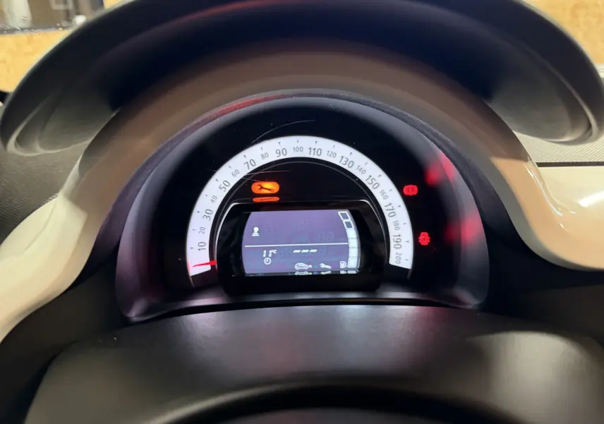 Vue rapprochée du tableau de bord numérique de la Renault Twingo III gris, affichant le compteur et voyants allumés.