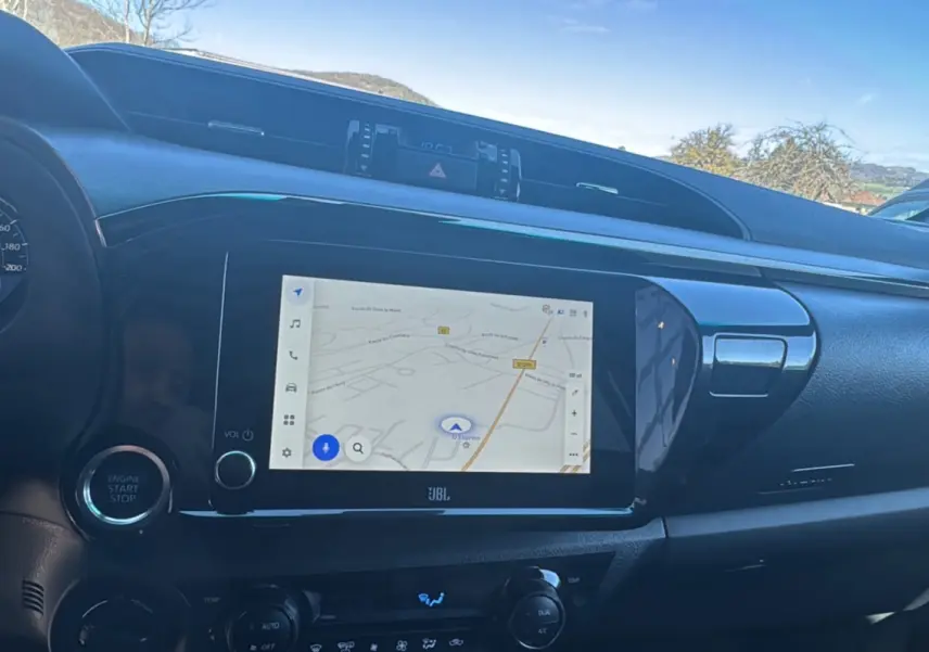 Vue intérieure du tableau de bord du Toyota Hilux 2026, écran tactile GPS 8 pouces et bouton start/stop visibles.