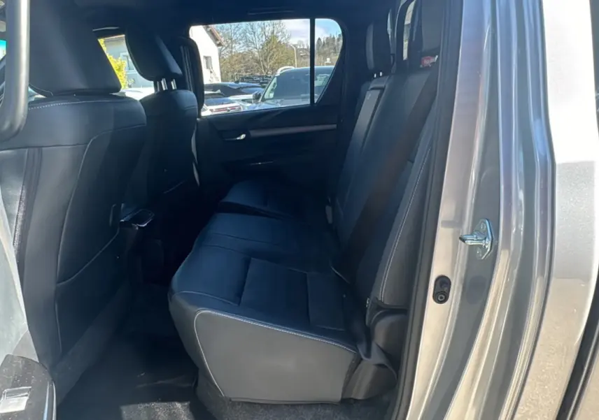 Vue intérieure arrière côté droit du Toyota Hilux 4x4 gris acier, montrant les sièges arrière en cuir noir.