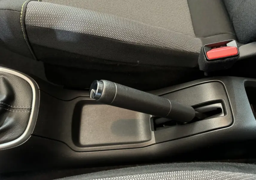 Vue rapprochée de la poignée de frein à main noire et du siège tissu gris dans une Citroën C3 2020.