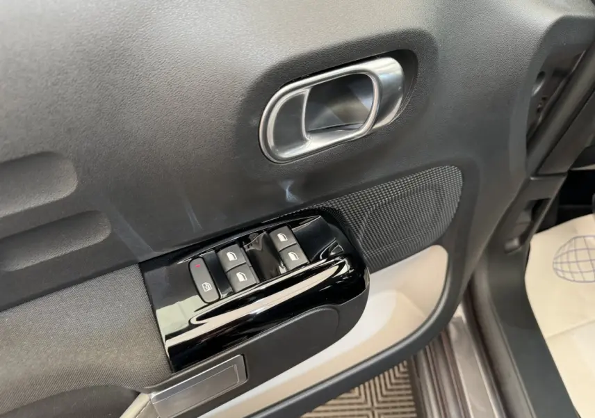 Gros plan sur la porte avant gauche grise d'une Citroën C3 2020, avec commandes de vitres et poignée argentée.