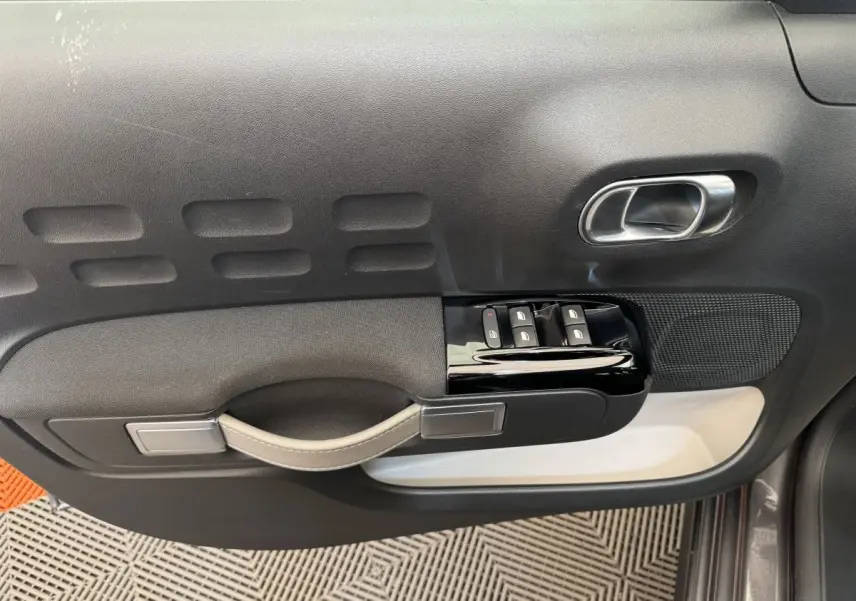 Vue rapprochée de la porte avant gauche gris foncé de la Citroën C3 avec commandes de vitres et poignée intégrée.