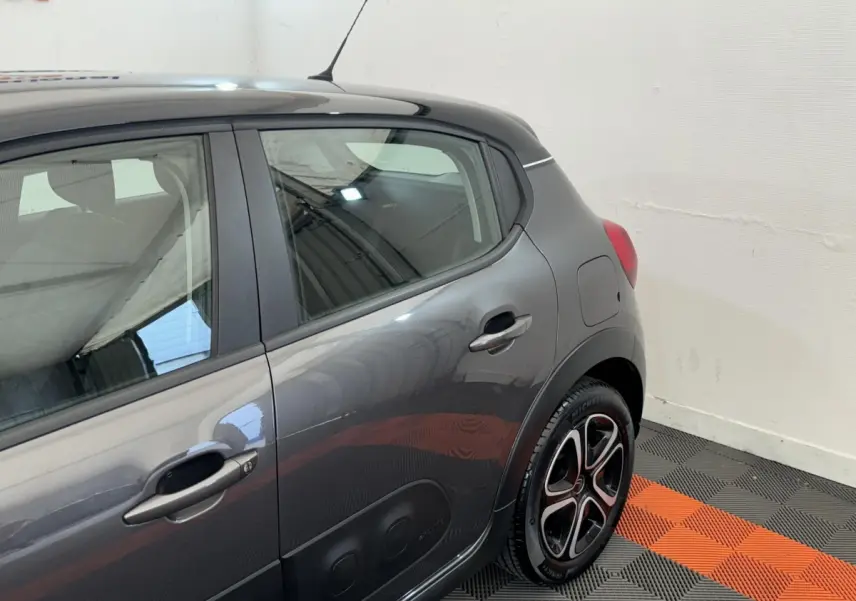 Vue côté droit arrière d'une Citroën C3 gris foncé avec protections latérales noires et jantes alliage bicolores.