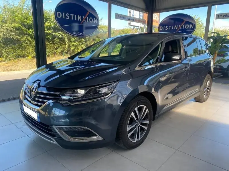 Renault Espace V gris métallisé vu en 3/4 avant droit dans un showroom avec jantes alliage et vitres teintées.