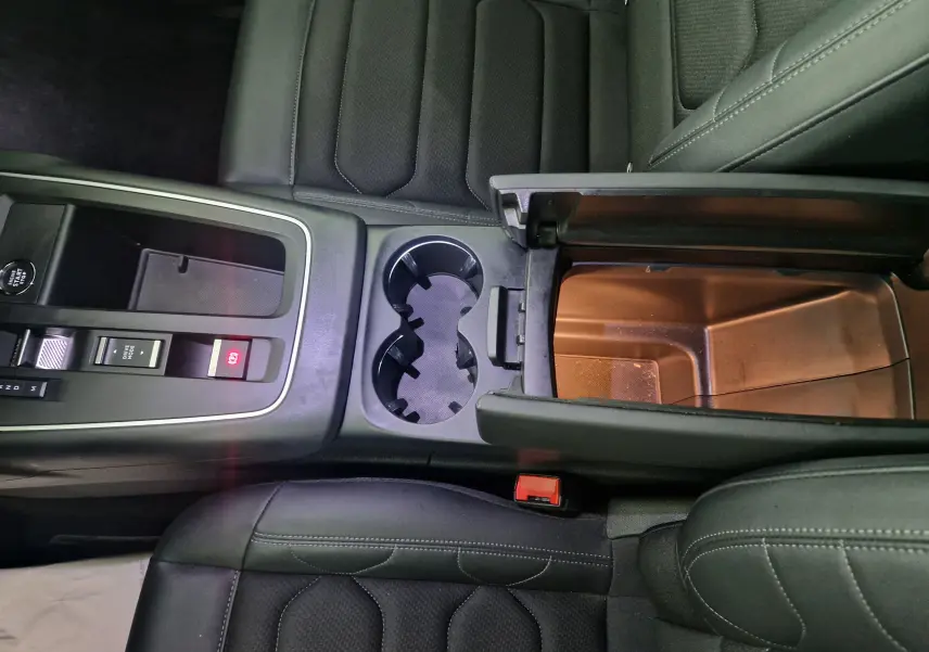 Vue plongeante sur la console centrale du Citroën C5 Aircross gris, avec accoudoir ouvert et sièges en cuir noir.