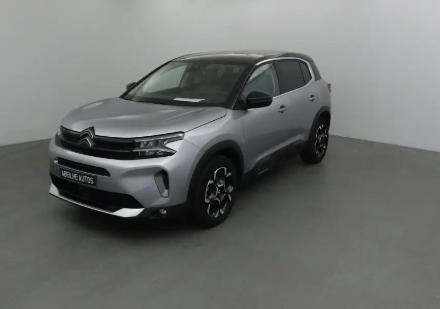 Citroën C5 Aircross 2024 gris Artense avec toit noir, vue 3/4 avant droit en intérieur neutre.