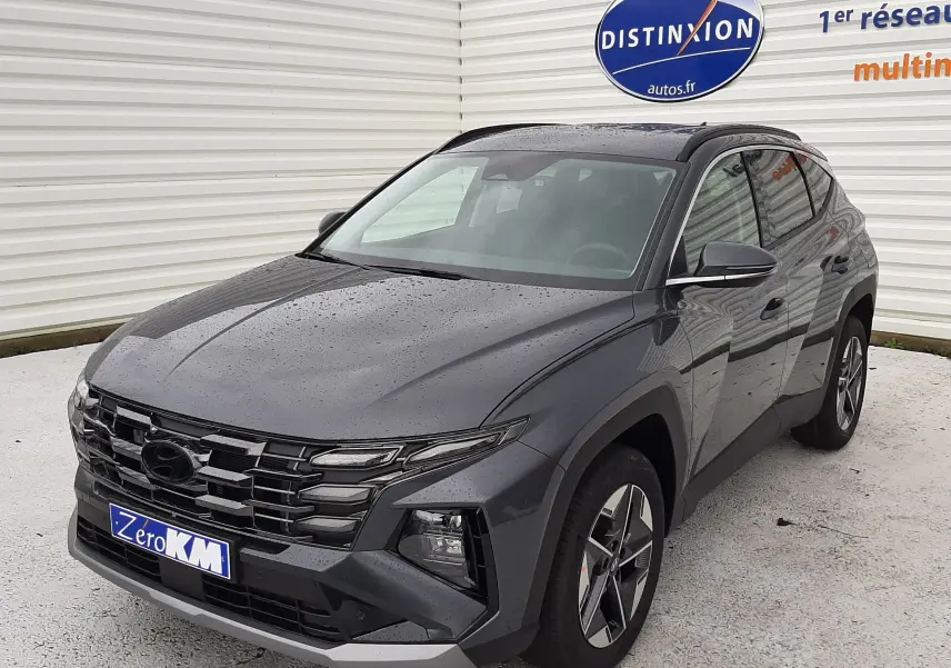Vue 3/4 avant d'un Hyundai Tucson 2025 gris Ecotronic, avec calandre imposante et jantes bi-ton visibles.