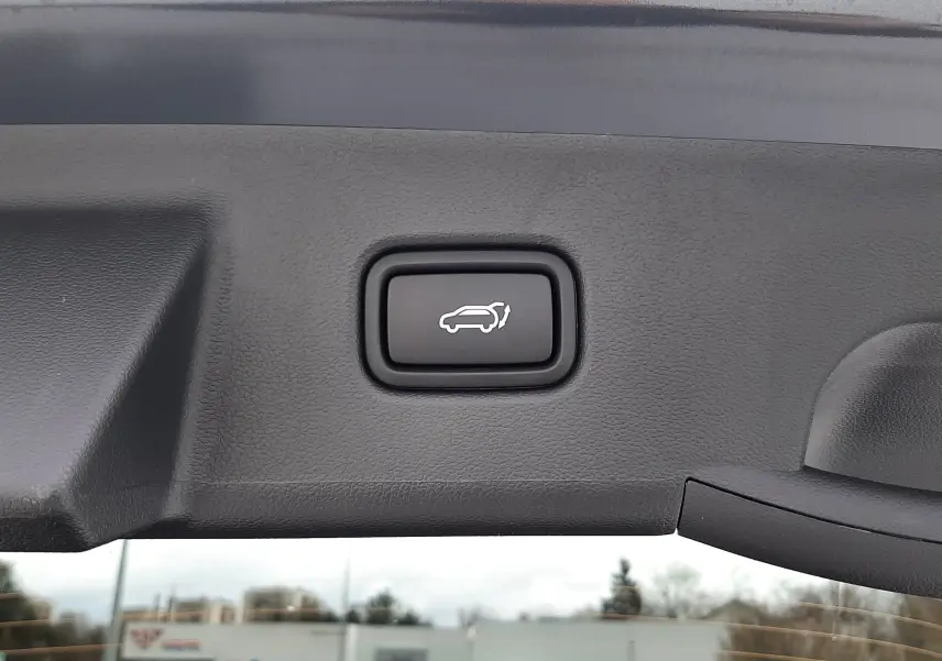 Gros plan sur le bouton d'ouverture électrique du hayon du Hyundai Tucson 2025 en gris Ecotronic.