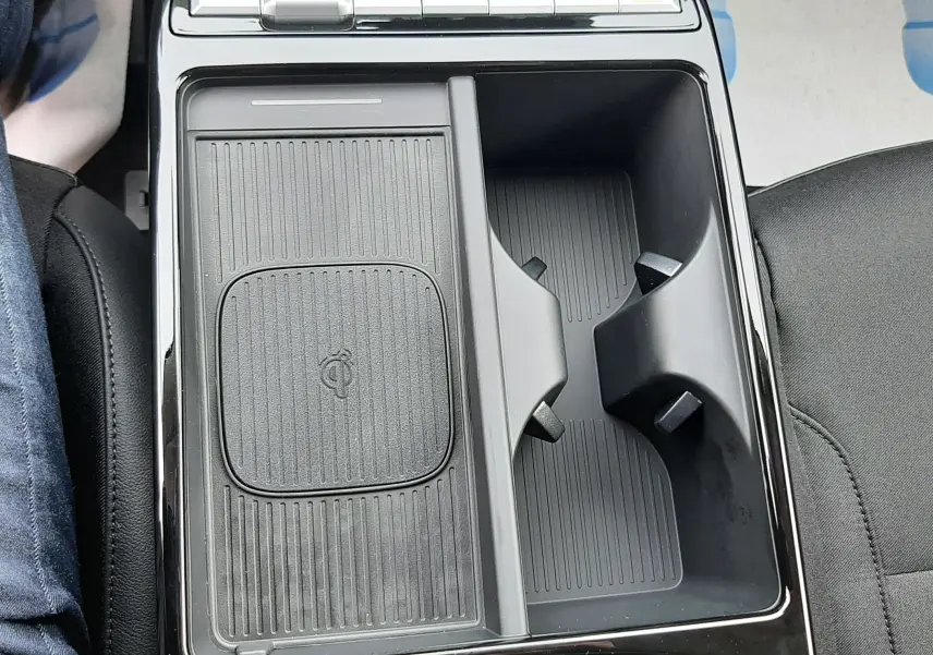 Vue plongeante sur la console centrale noire du Hyundai Tucson 2025, avec zone de recharge sans fil et porte-gobelets.