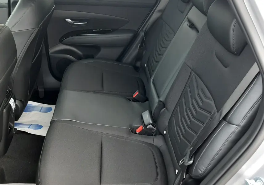 Vue intérieure côté droit des sièges arrière noirs en tissu et cuir du Hyundai Tucson 2025, avec portières ouvertes.
