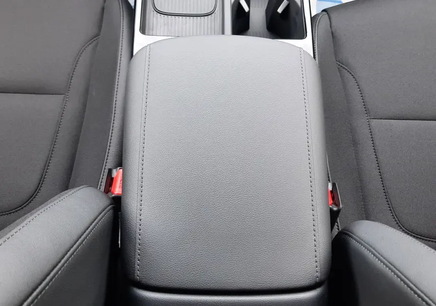 Vue intérieure centrée sur l'accoudoir central gris clair et les sièges noirs du Hyundai Tucson 2025 hybride.