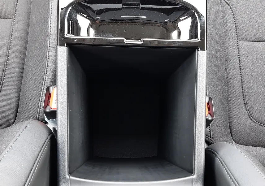 Vue plongeante sur le rangement central ouvert de l’habitacle gris foncé du Hyundai Tucson 2025, avec accoudoirs en tissu.