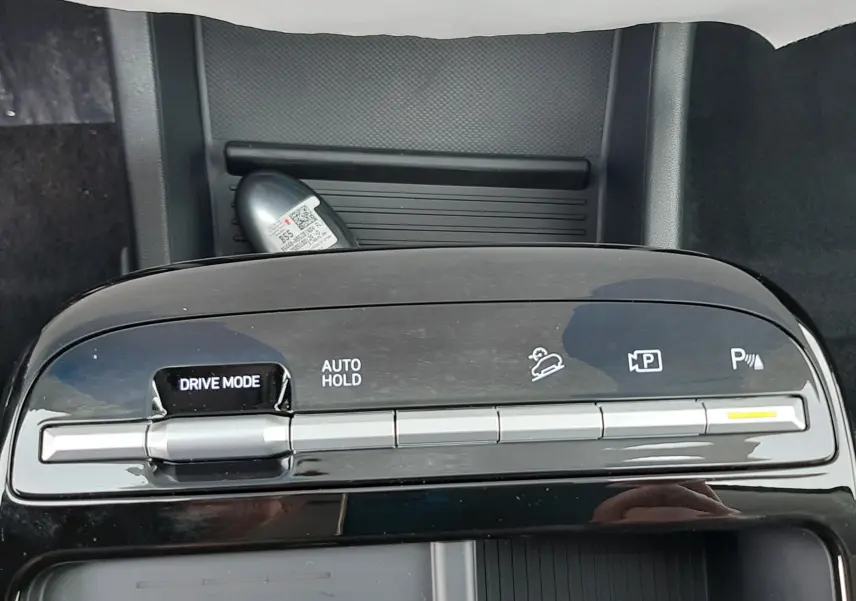 Gros plan sur la console centrale noire du Hyundai Tucson 2025, avec commandes Drive Mode et Auto Hold visibles.