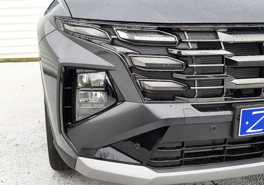 Gros plan sur l'avant droit du Hyundai Tucson 2025 gris Ecotronic, mettant en valeur la calandre et les phares LED distinctifs.