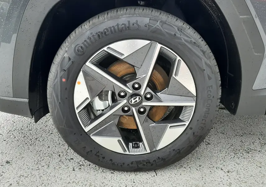 Gros plan sur la roue avant gauche du Hyundai Tucson 2025 gris Ecotronic avec jante alliage bicolore et logo Hyundai central.