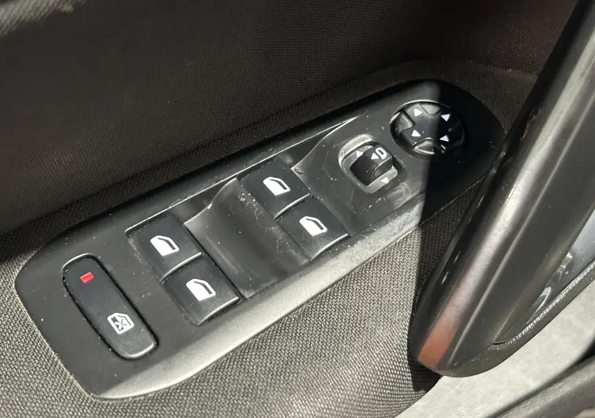 Gros plan sur les commandes de lève-vitres et rétroviseurs côté conducteur d’une Peugeot 308 SW noire de 2018.