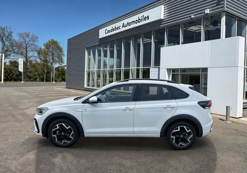 Profil droit d'un Volkswagen Taigo blanc 2025 avec jantes alliage et seuils de porte R-Line devant un concessionnaire.