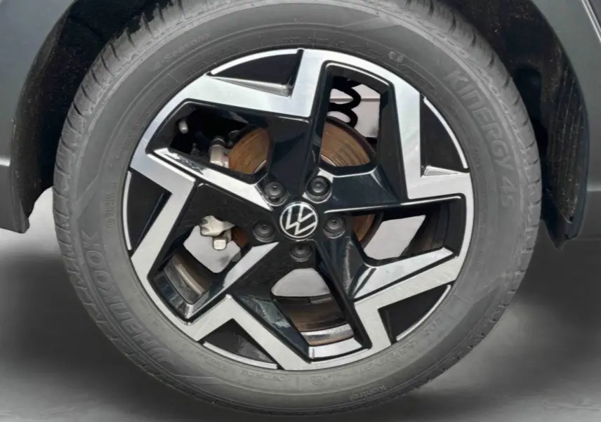 Gros plan sur la jante alliage noir et argentée avec logo Volkswagen, roue avant droite du Volkswagen Taigo blanc.