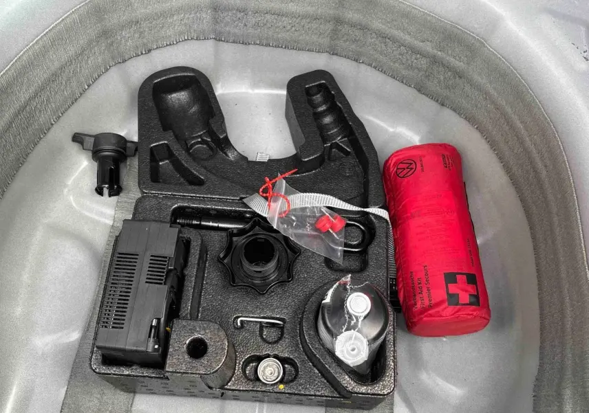 Gros plan sur le coffre à outils et trousse de secours rouge du Volkswagen Taigo blanc, vue de dessus.
