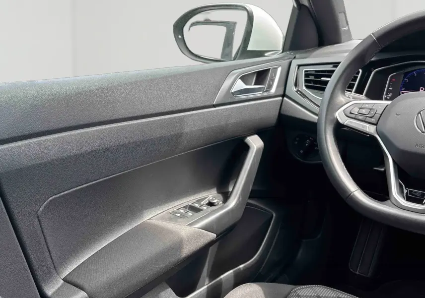 Vue intérieure côté conducteur du Volkswagen Taigo 2025, montrant la portière noire et le volant cuir multifonctions avec logo R-Line.