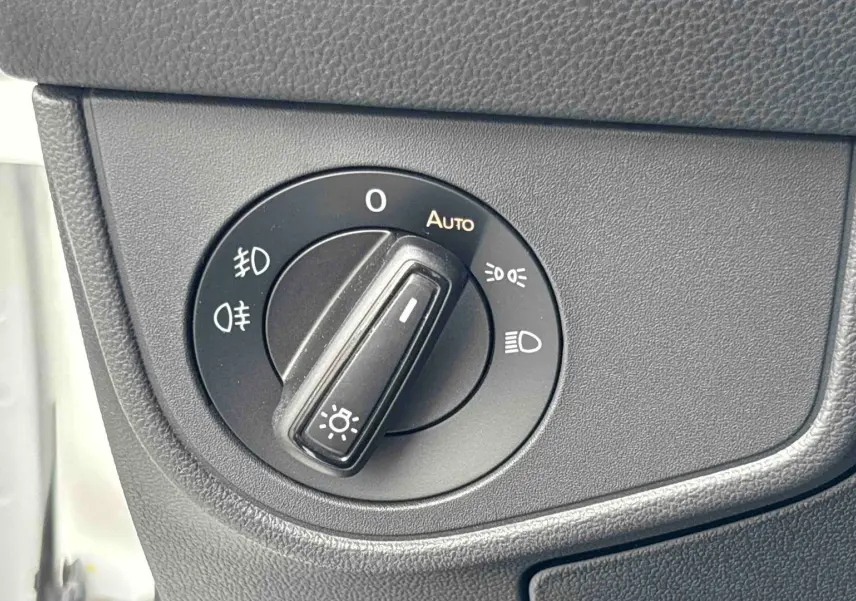 Gros plan sur le bouton de commande des phares dans l’habitacle du Volkswagen Taigo blanc, côté gauche.