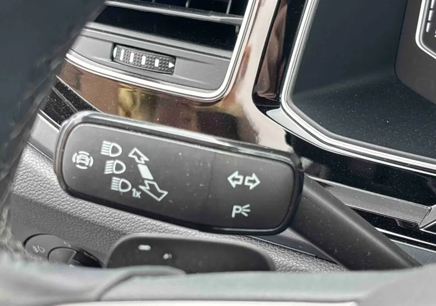Gros plan sur la manette de clignotant et feux du Volkswagen Taigo 2025, intérieur noir avec détails chromés.