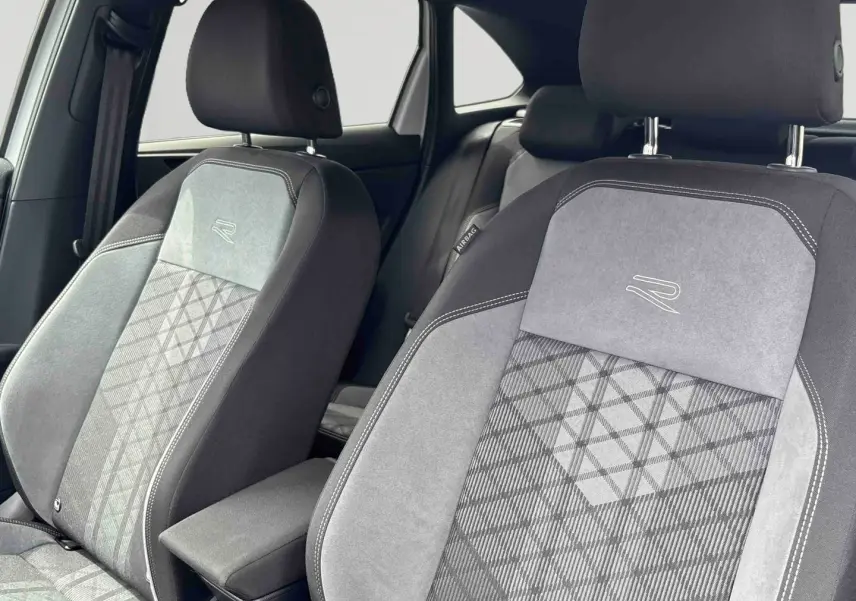 Gros plan sur les sièges avant gris et noirs avec logo R-Line brodé, intérieur du Volkswagen Taigo 2025.