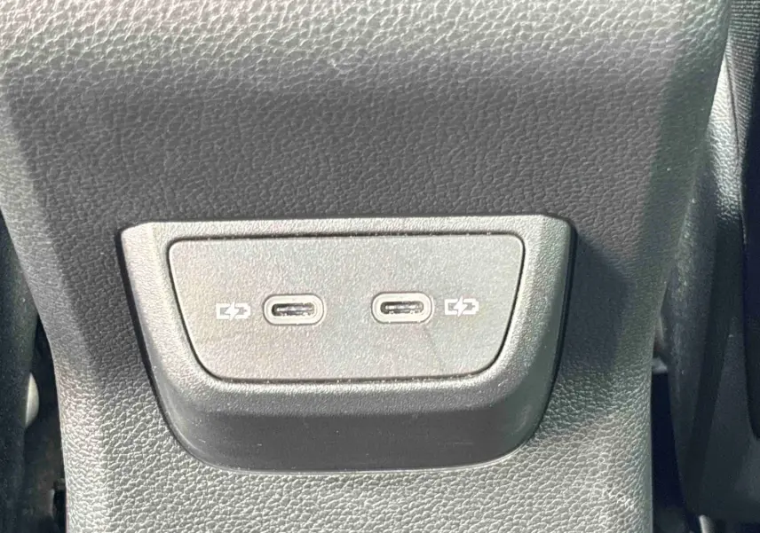 Gros plan sur deux ports USB-C pour charge situés à l'arrière d'un Volkswagen Taigo blanc.
