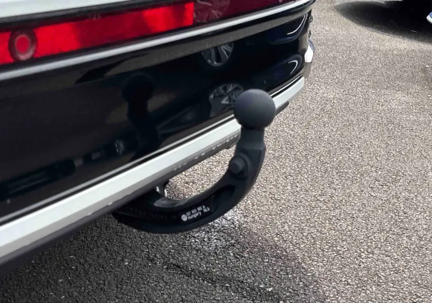 Gros plan sur l'attelage amovible noir sous le pare-chocs arrière blanc du Volkswagen Taigo.