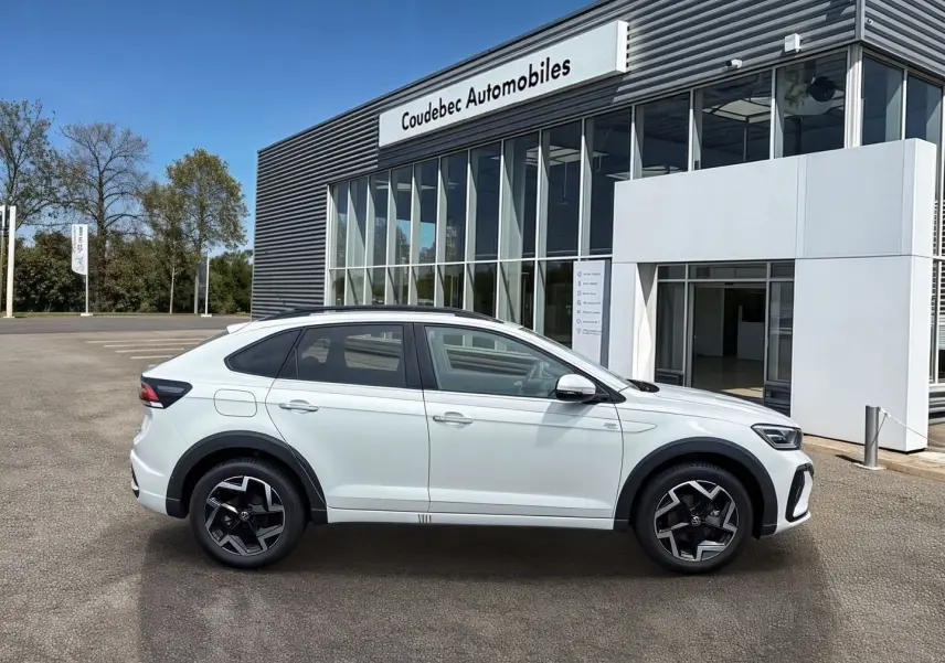 Profil droit du Volkswagen Taigo blanc 2025 avec jantes alliage noires et détails R-Line devant un concessionnaire.