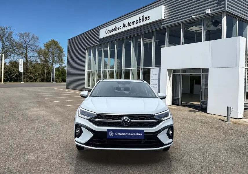 Vue de face du Volkswagen Taigo blanc 2025 avec calandre R-Line et projecteurs Matrix LED devant un concessionnaire.