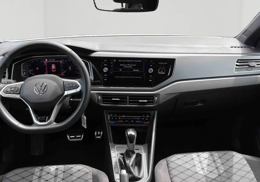 Vue intérieure avant du Volkswagen Taigo blanc 2025, volant multifonction et écran tactile central visible.