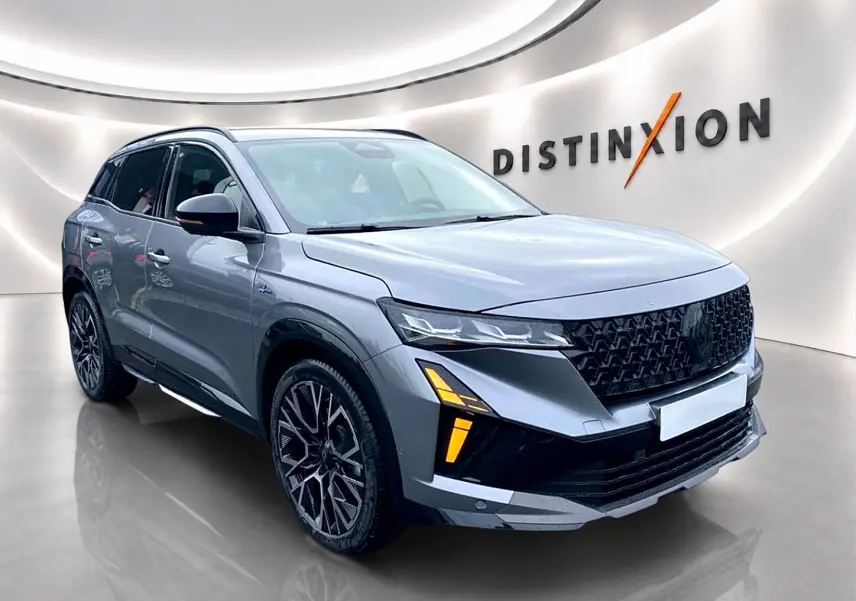 Renault Austral gris schiste en 3/4 avant droit, avec calandre noire et feux LED distinctifs allumés.