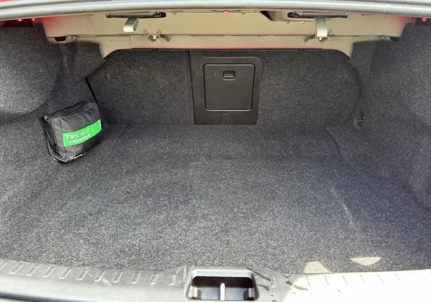 Coffre spacieux de Volvo S60 B4 197 DCT7 MHEV Core+ 2024, vue intérieure, tapis gris et trousse de secours.