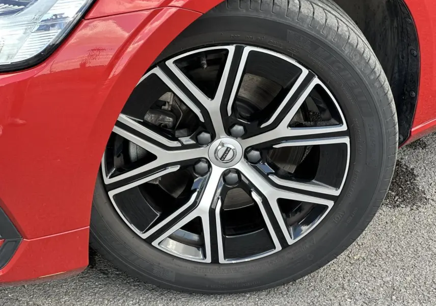 Gros plan sur la jante alliage 17 pouces noir et diamant du côté avant gauche d'une Volvo S60 Rouge Fusion 2024.